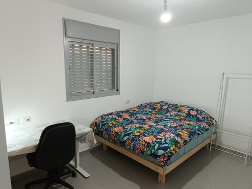 um quarto com uma cama, uma secretária e uma janela em Lovely room at Benny's apartment em Netivot