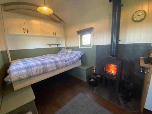 a bedroom with a bed and a wood stove at Spring Grounds Farm Shepherd Huts 
