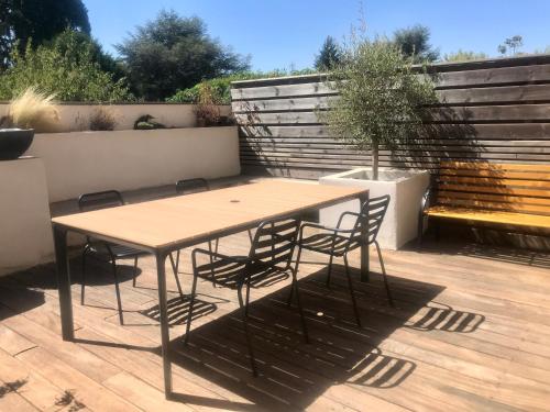 a wooden table and chairs on a patio at Charmant appartement Saint Cyr au mont d’or in Saint-Romain-au-Mont-dʼOr