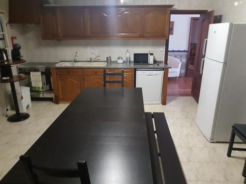 a kitchen with a black table and a white refrigerator at Quinta da Paz in Borba