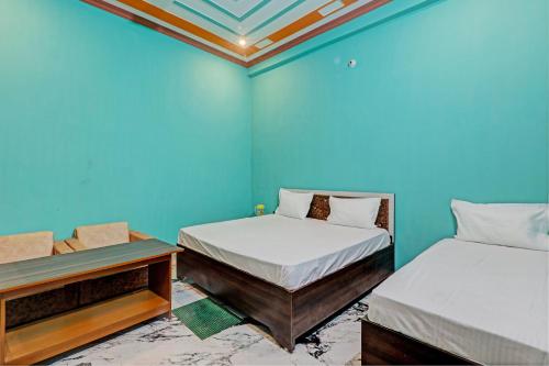 two beds in a room with blue walls at OYO Green Valley Guest House in Sultānpur