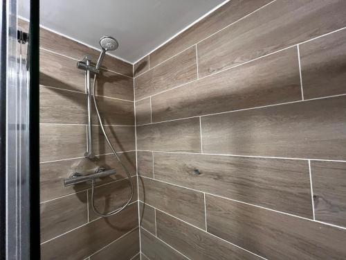 ein Bad mit einer Dusche und Holzwänden in der Unterkunft Central flat, Alton Towers, Waterworld in Stoke on Trent