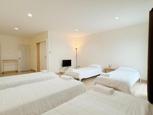 a room with three beds and a television at Jira Simply room Suvarnabhumi Airport 15 mins in Ban Khlong Prawet