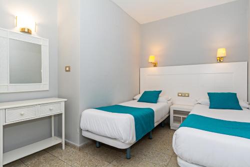 a bedroom with two beds and a mirror at Apartamentos Panorama Adults Only in Puerto del Carmen