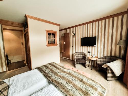 a bedroom with a bed and a tv and a chair at Landhaus Talblick- Frühstückspension in Brotterode-Trusetal