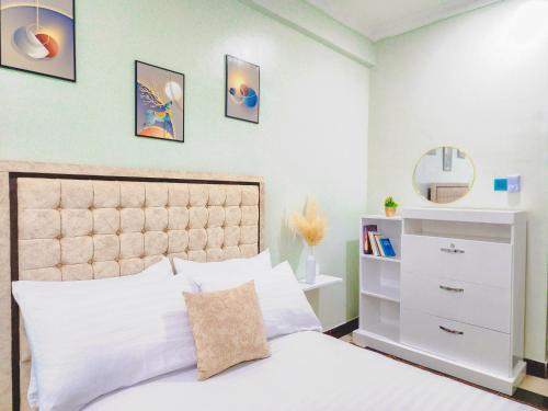 a bedroom with a white bed and a mirror at Fefe's home in Dar es Salaam