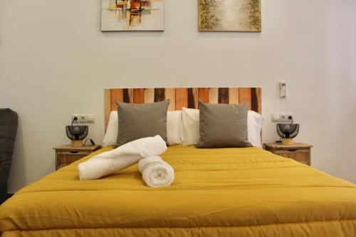 Una cama amarilla con dos rollos de toallas. en NUEVO ESTUDIO DIVINA PASTORA N-1, en Málaga