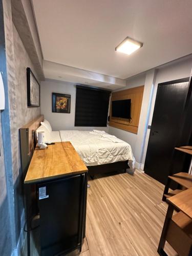Habitación pequeña con cama y escritorio en Hotel La Serena, en Maresias