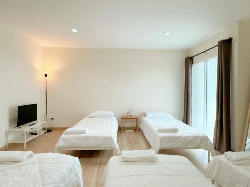 a room with three beds and a flat screen tv at Jira Private simply room near Suvarnabhumi Airport in Ban Khlong Prawet