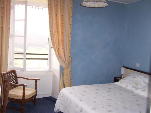 a bedroom with a bed and a chair and a window at Auberge Hôtel de Tournemire - Cantal in Tournemire