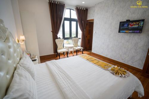 a bedroom with a large white bed and two chairs at Hoàng Gia Hotel Tuy Hoà in Tuy Hoa