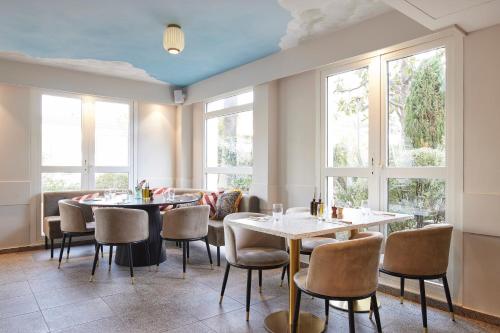 ニースにあるHotel-Restaurant Isidore Nice Ouestのテーブルと椅子、窓のあるレストラン