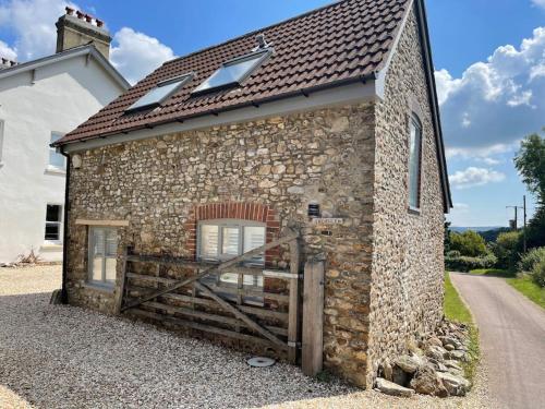 a stone building with a wooden gate and a barn at The Stable at Thornlea in Axminster