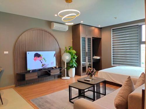 a living room with a bed and a flat screen tv at Mon Cherry Apartment -Greenbay Garden Ha Long in Ha Long