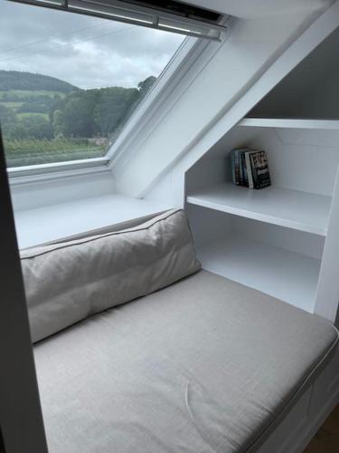 a bed sitting in a room with a window at The Stable at Thornlea in Axminster