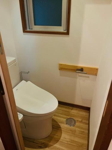a small bathroom with a toilet and a window at Snow Palace Nozawa in Nozawa Onsen