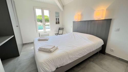 Un dormitorio con una cama blanca con toallas. en Superbe villa avec piscine chauffée, proche mer, en Ars-en-Ré