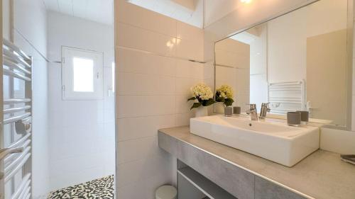 Baño blanco con lavabo y espejo en Superbe villa avec piscine chauffée, proche mer, en Ars-en-Ré