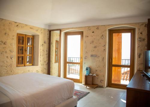 a bedroom with a bed and two windows at Zoe Hora in Dhërmi