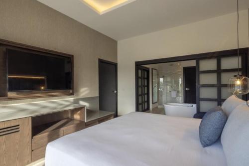 a bedroom with a bed and a television and a tub at Royalton Hideaway Blue Waters, An Autograph Collection All-Inclusive Resort - Adults Only in Falmouth
