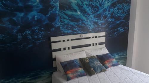 a bed with two pillows in a bedroom with a mural at alquiler temporario en Córdoba Capital, excelente ubicación in Cordoba