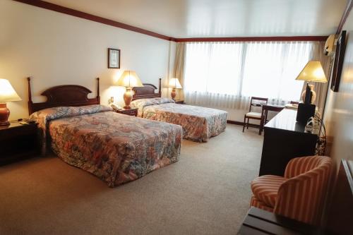 a hotel room with two beds and a desk at Nobile Suites Excelsior Asuncion in Asuncion