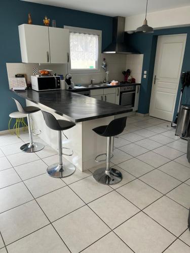 une cuisine avec une table et deux tabourets de bar dans l'établissement Villa le jasmin très calme, à Andrézieux-Bouthéon