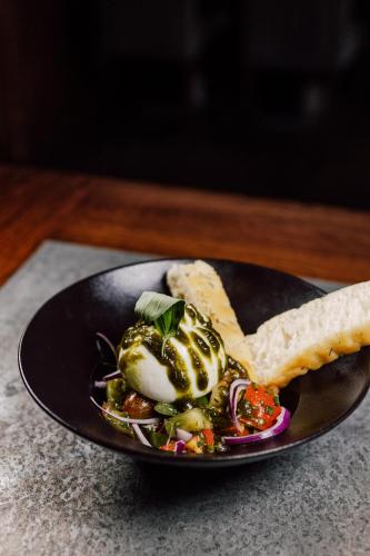a black plate of food with a salad and bread at Bellevue in Les Gets