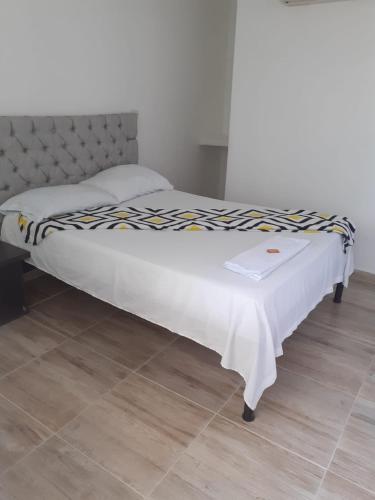 a bed in a bedroom with a white blanket on it at caribepremiumvalledupar in Valledupar