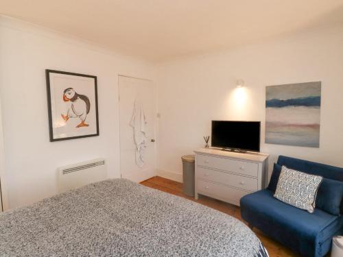 a bedroom with a bed and a chair and a television at 6 Hillside Terrace in Dartmouth