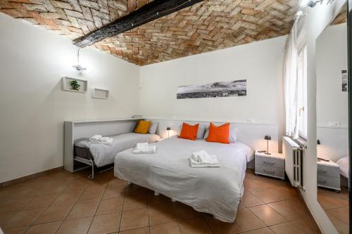 1 dormitorio con 2 camas con almohadas de color naranja en Le Volte, en Módena