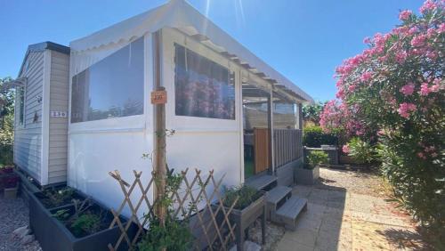Mobil home (Clim, Lv, Ll)- Camping Vic-la-Gardiole 4* - 012 في فيك- لا-غارديول: منزل صغير في حديقة بها زهور