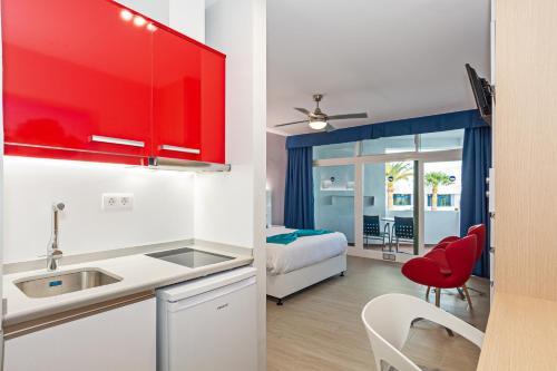 a kitchen with red cabinets and a bedroom with a bed at Apartamentos Panorama Adults Only in Puerto del Carmen