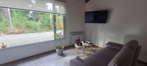 a living room with a couch and a large window at Cactus Tempo in Esquel