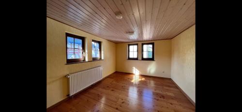 an empty room with two windows and a wooden floor at Ferienwohnung Dillenburg Jung in Dillenburg