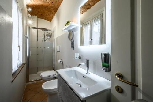 a white bathroom with a sink and a toilet at Le Volte in Modena