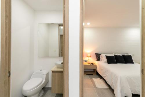 a bedroom with a bed and a sink and a toilet at Borbon Suites in Medellín