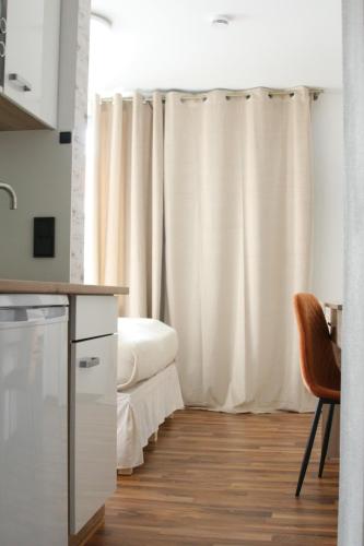 a kitchen with white curtains and a bed in a room at The Manhattan A Boutique Hotel By American Ease in Gravenwerth