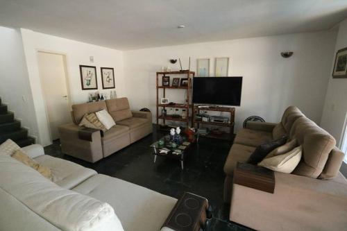 a living room with two couches and a flat screen tv at Casa em Jardim Acapulco-Guarujá in Guarujá