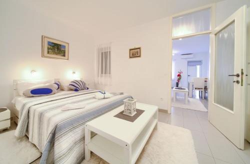 biała sypialnia z dużym łóżkiem i stołem w obiekcie Apartments Škarpa w mieście Malinska