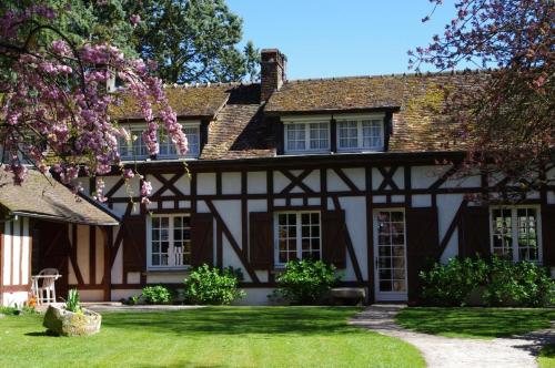 an old black and white house with a yard at La Vallée in Hébécourt