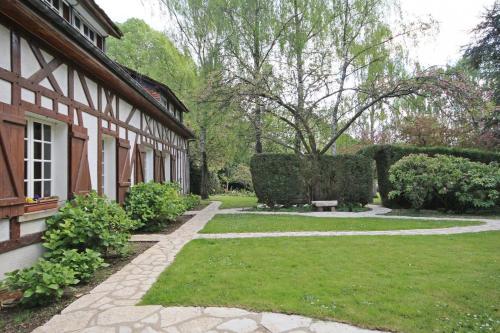 a garden next to a house with a lawn at La Vallée in Hébécourt