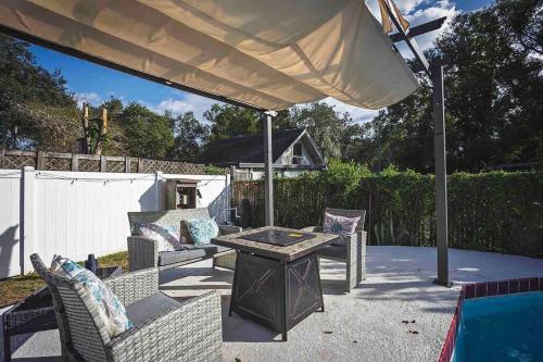 a patio with a table and chairs under an umbrella at Heated Pool in Private House w/ Fire Pit in Seffner