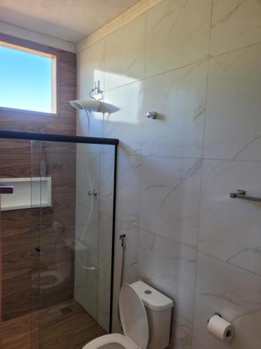 a bathroom with a toilet and a glass shower at Chalé Praia Vermelha 1 in Delfinópolis