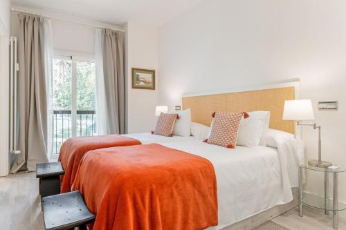 a bedroom with two beds with an orange blanket at Apartamento Enfrente Palacio Royal Palace I in Madrid
