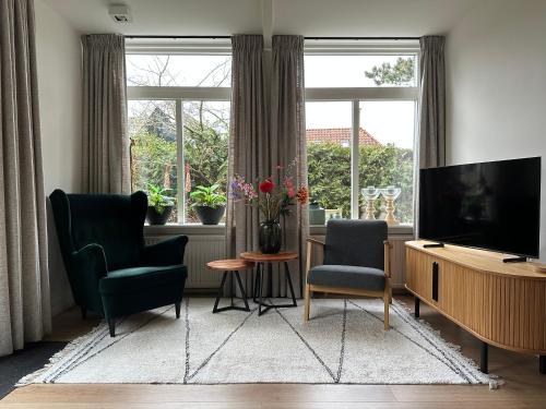 a living room with two chairs and a flat screen tv at De Lijster in Bergen