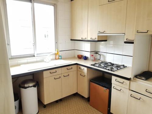 une cuisine avec des armoires blanches et un four à plaques de cuisson dans l'établissement Agréable Apartment 2 pièces, à Boulogne-Billancourt