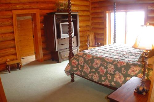 a bedroom with a bed and a television in a log cabin at Picture Perfect in West Jefferson
