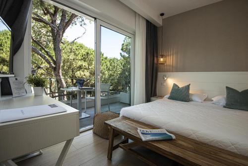 リニャーノ・サッビアドーロにあるSuite Erica Lignano Hotelのベッドルーム1室(ベッド1台付)、バスルーム(窓付)が備わります。