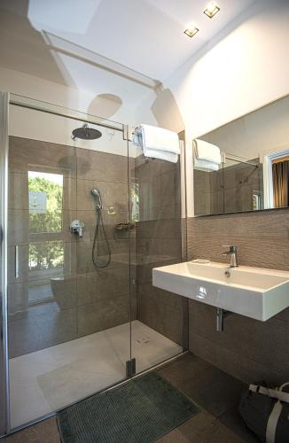 a bathroom with a glass shower and a sink at Suite Erica Lignano Hotel in Lignano Sabbiadoro